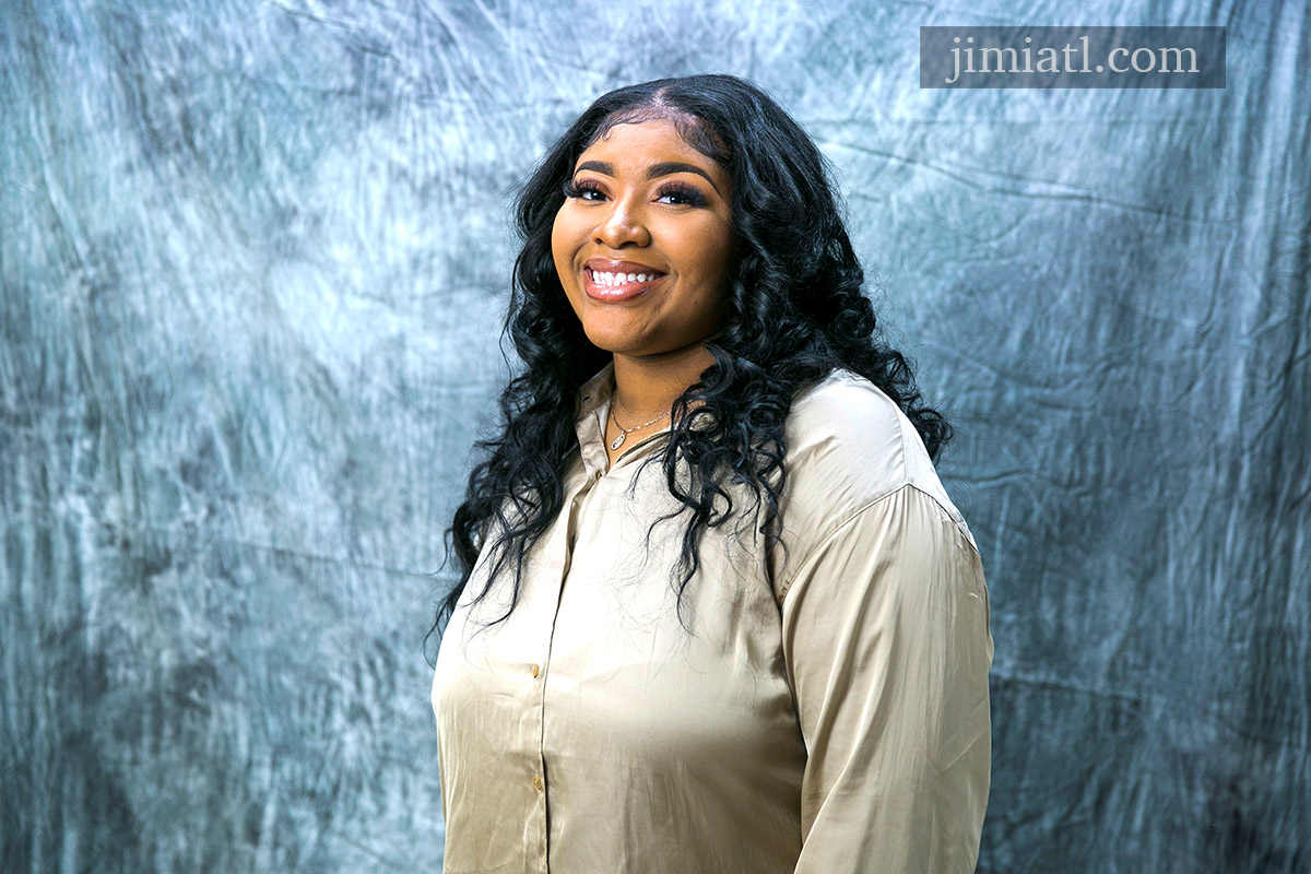 Smiling woman takes studio headshot photograph with Jimi A Productions.